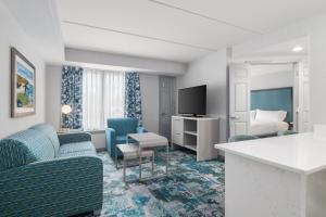 a hotel room with blue chairs and a bed at Homewood Suites Williamsburg in Williamsburg