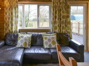 a leather couch in a living room with windows at Treehouse Cabin in Westward