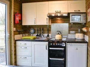 a kitchen with white cabinets and a stove at Treehouse Cabin in Westward