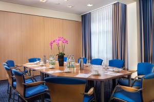a conference room with a long table and blue chairs at Tryp by Wyndham Luebeck Aquamarin in Lübeck