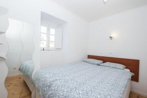 Castelo Terrace في لشبونة: غرفة نوم بيضاء بها سرير ونافذة
