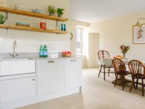 a kitchen with white cabinets and a table at West Skeroblin in Campbeltown