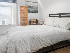 a bedroom with a bed and a dresser and a window at Ernies in Haverigg