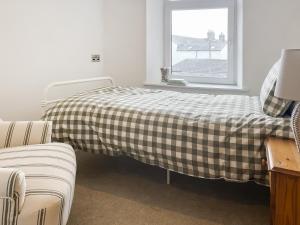 a bed with a checkered blanket in a room with a window at Ernies in Haverigg +3 photos