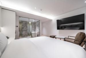 a white bedroom with a large bed and chairs at 서초 Hotel Brick in Seoul