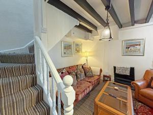 a living room with a couch and a staircase at The Courtyard Cottage in Llangollen