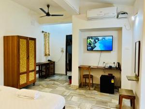 a bedroom with a desk and a tv on the wall at Peravel Beach Holiday Home in Candolim