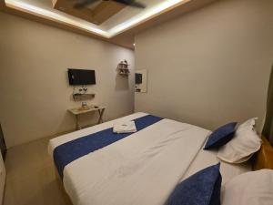 a bedroom with a large bed and a tv at Vijaya Lodge in Vadalūr