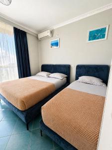 two beds sitting in a room with a window at Eri Apartments 2 in Shëngjin +18 photos