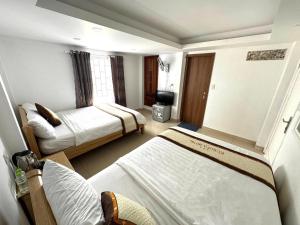 a hotel room with two beds and a television at Europa Hotel in Da Lat