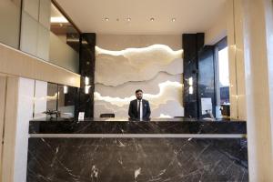 a man in a suit standing in a lobby at Hotel Midtown in Surat
