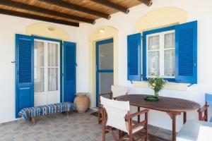 a patio with blue shutters and a wooden table and chairs at Hippocrates' House in Amorgos