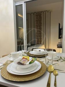 a table with white plates and silverware on it at Cobblestone Properties - SM Mezza 1 Residences in Manila