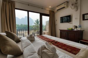 a bedroom with a large bed with a large window at The Elephant Crossing Hotel in Vang Vieng +130 photos