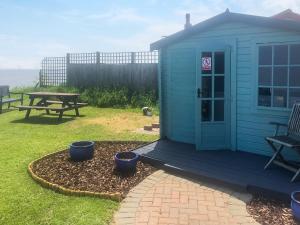 a blue shed with a picnic table and a bench at No 4 Hickling Chalet - Uk51729 in Scratby