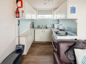 a small kitchen with white cabinets and a stove at No 4 Hickling Chalet - Uk51729 in Scratby
