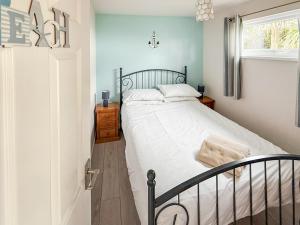 a bedroom with a bed with white sheets and a window at No 4 Hickling Chalet - Uk51729 in Scratby