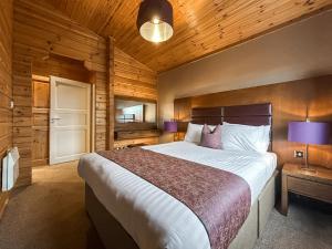 a bedroom with a large bed and wooden walls at Lodge 3 - Uk51250 in Glasgow