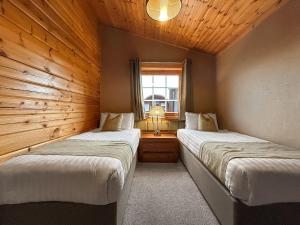 two beds in a room with wooden walls at Lodge 3 - Uk51250 in Glasgow