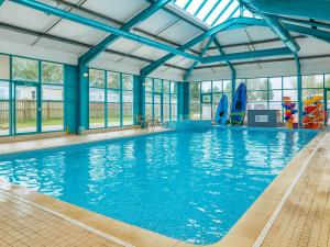 a large swimming pool with blue ceilings and windows at The Medway - Uk51004 in Eastchurch