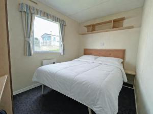 a small bedroom with a bed with a window at The Medway - Uk51004 in Eastchurch