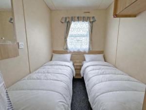 three beds in a small room with a window at The Medway - Uk51004 in Eastchurch