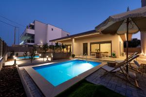 a swimming pool in front of a house at night at Olivio 4 Seasons Villas in Nea Moudania