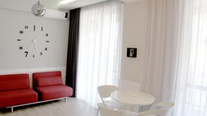 een rode stoel en een tafel en een klok aan een muur bij Happy Apartment 7 in Tbilisi City