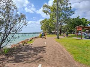 a walkway in a park next to the water at Waters Edge in Urangan +6 photos