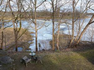 a table and chairs sitting next to a river at Zelta Apelsīna Rezidences in Kuldīga