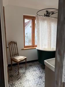 a bathroom with a tub and a chair and a window at Zelta Apelsīna Rezidences in Kuldīga
