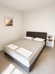 a bed in a room with a white wall at Horizont Dobre Vode in Dobra Voda