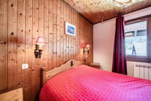 a bedroom with a red bed and wooden walls at La Pointe des Mattes in La Chapelle-dʼAbondance