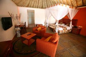 ein Schlafzimmer mit einem Bett, zwei Stühlen und einem Tisch in der Unterkunft Seasons Elementaita Country Lodge in Nakuru