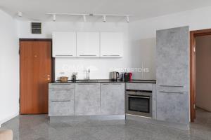 a kitchen with stainless steel appliances and white cabinets at Blue Seacliff Luxe in Komoševina +5 photos