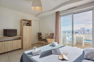 a hotel room with a bed and a balcony at Résidence Odalys Le Lotus Blanc in Le Barcarès