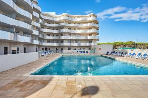 a swimming pool in front of a building at Résidence Odalys Le Lotus Blanc in Le Barcarès