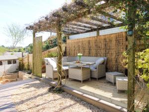 a patio with a table and chairs under a pergola at Park Cottage in Kingsbridge