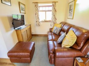 a living room with a brown leather couch and a television at Ticklepenny in Louth