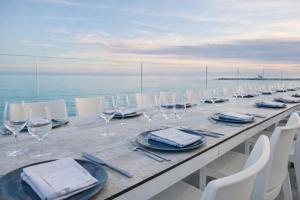 a long table with wine glasses and white chairs at Hotiday Rooms Torre Pali in Torre Pali