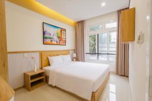 a bedroom with a white bed and a window at Palmier Hotel - Art House Da Nang in Danang