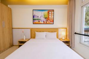 a bedroom with a white bed and a window at Palmier Hotel - Art House Da Nang in Danang