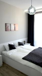 een witte slaapkamer met een groot wit bed met zwarte kussens bij Happy Apartment 7 in Tbilisi City