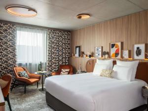 a hotel room with a large bed and chairs at Pullman Lyon in Lyon