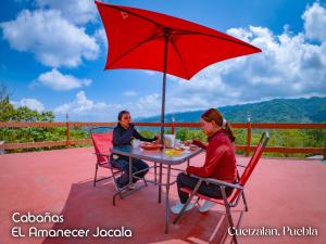a man and woman sitting at a table under an umbrella at Cabañas el amanecer Jacala in Cuetzalán del Progreso