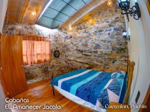 a bedroom with a bed in a stone wall at Cabañas el amanecer Jacala in Cuetzalán del Progreso +2 photos