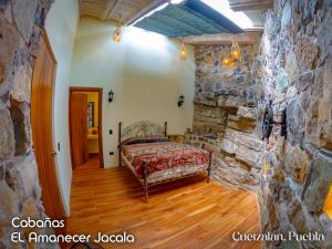 a bedroom with a bed in a stone wall at Cabañas el amanecer Jacala in Cuetzalán del Progreso