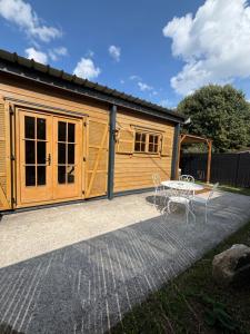 a wooden cabin with a table and a patio at Chalet Des Aigrettes- Jacuzzi privatif in Chassey-lès-Montbozon