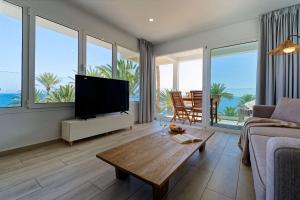 a living room with a flat screen tv and large windows at Deva Beach Boutique Apartments in San Bartolomé