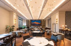 a restaurant with tables and chairs and a large screen at JOY Hotel Hangzhou in Hangzhou